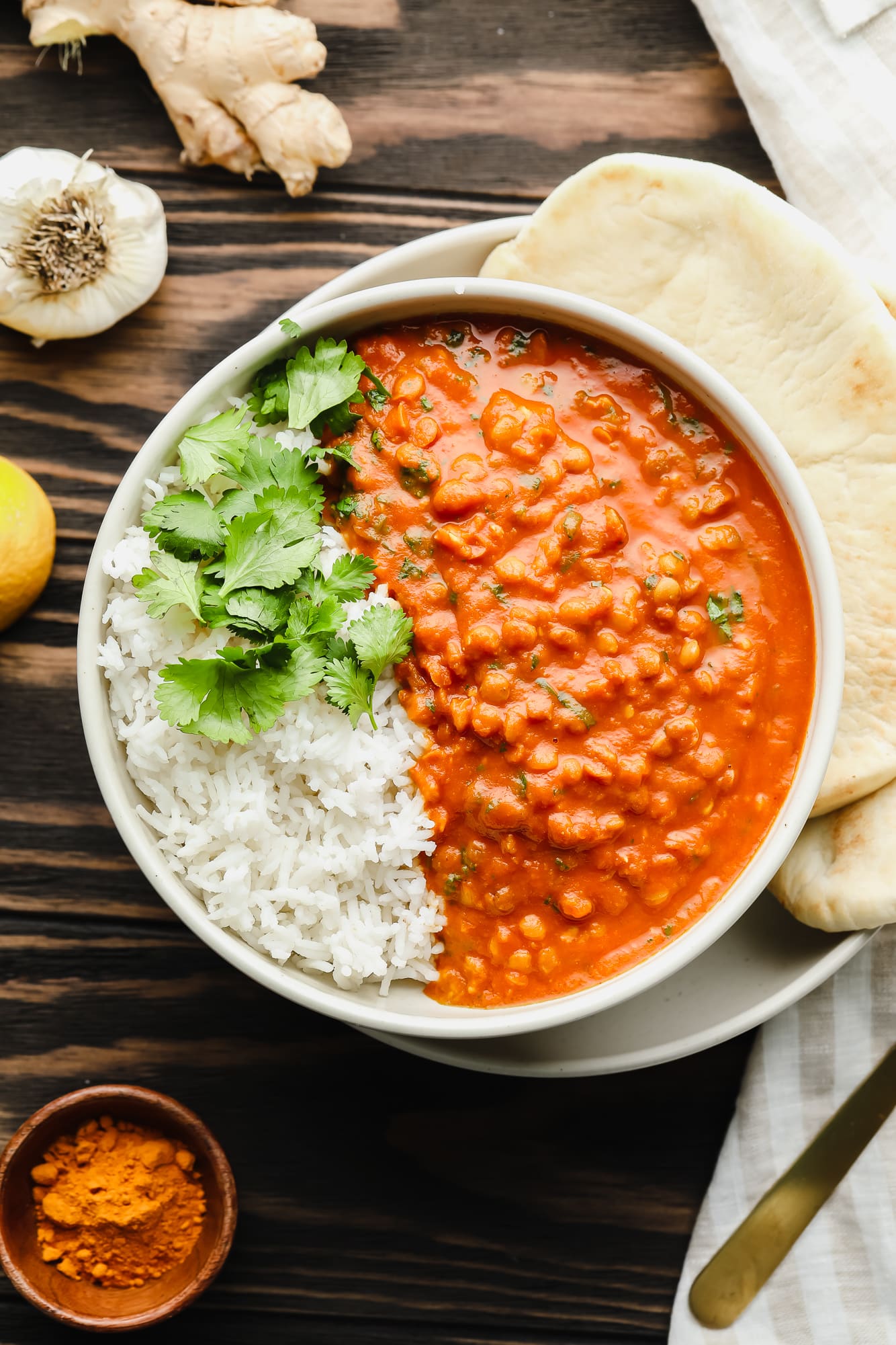 lentil curry with white rice and cilantro in a large bowl with naan on the side.