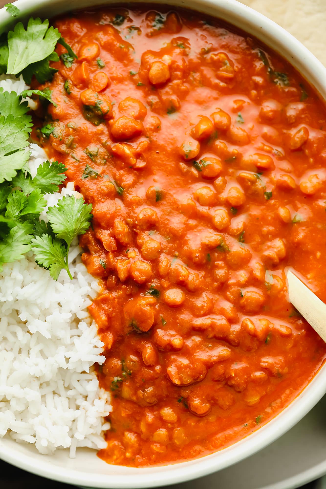 close up on lentil curry with white rice in a white bowl.