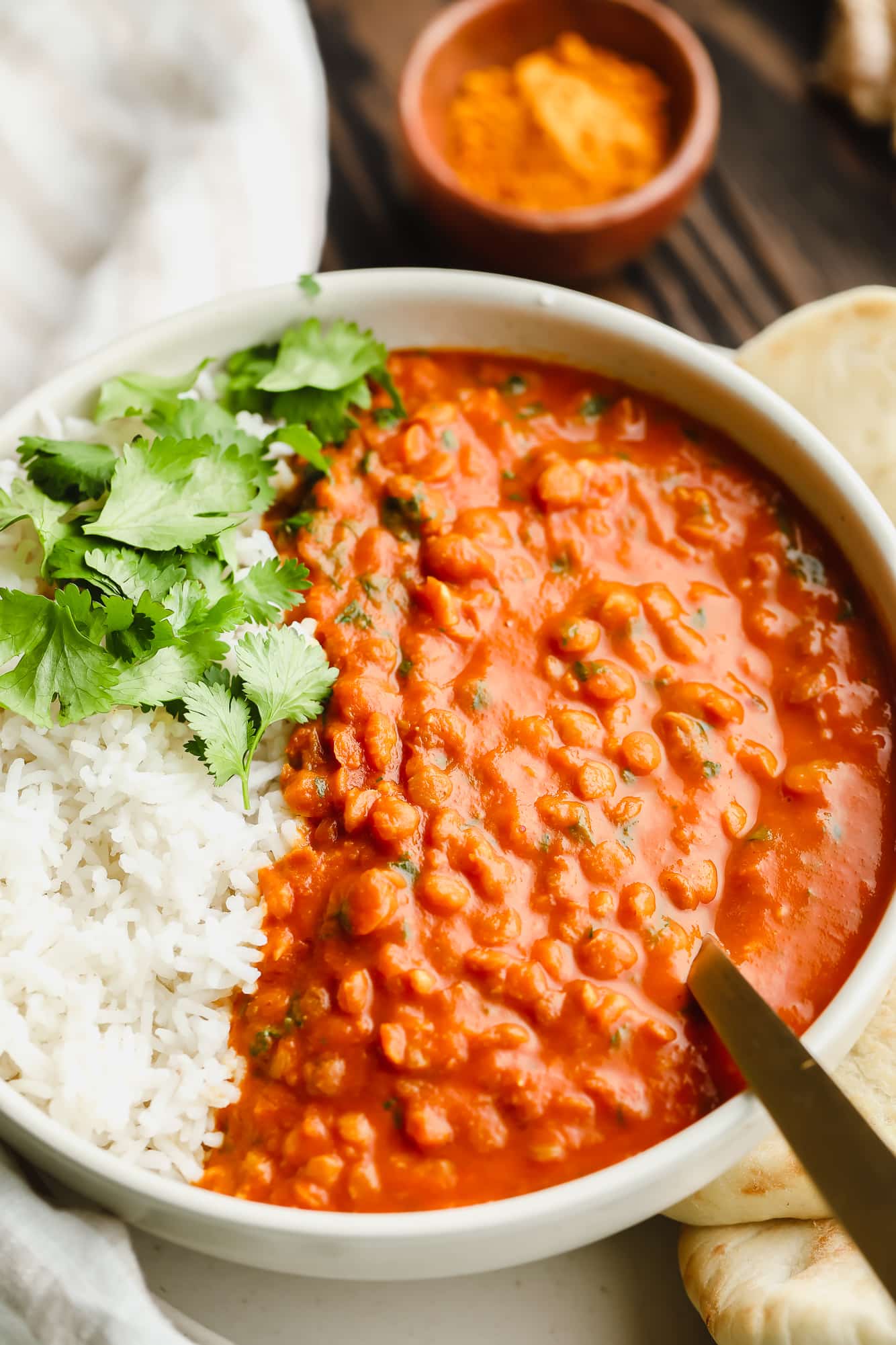 close up on lentil curry with white rice in a white bowl.