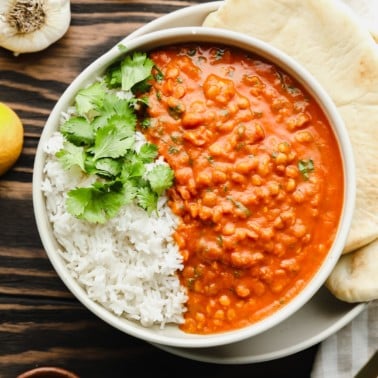 close up on lentil curry with white rice in a white bowl.