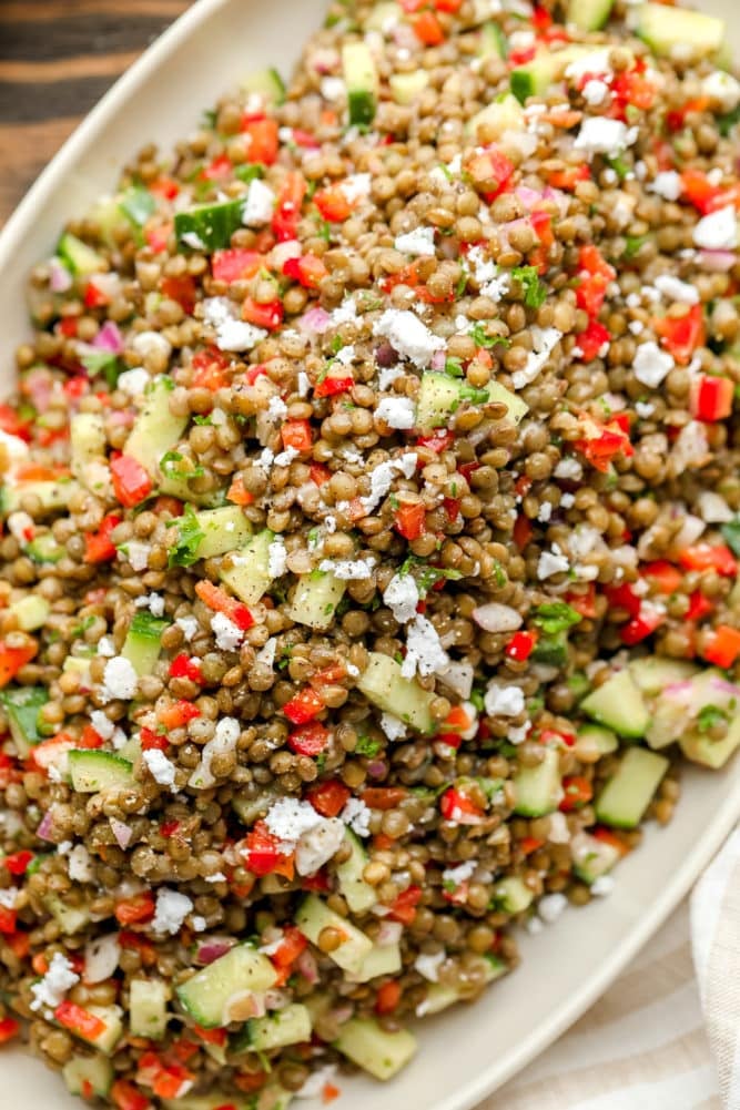 close up of lentils and vegetables with crumbled cheese on a plate