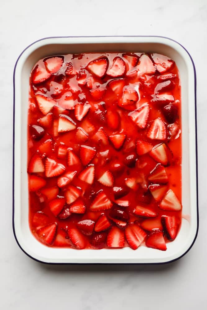 strawberries in sauce in a white pan with blue edge