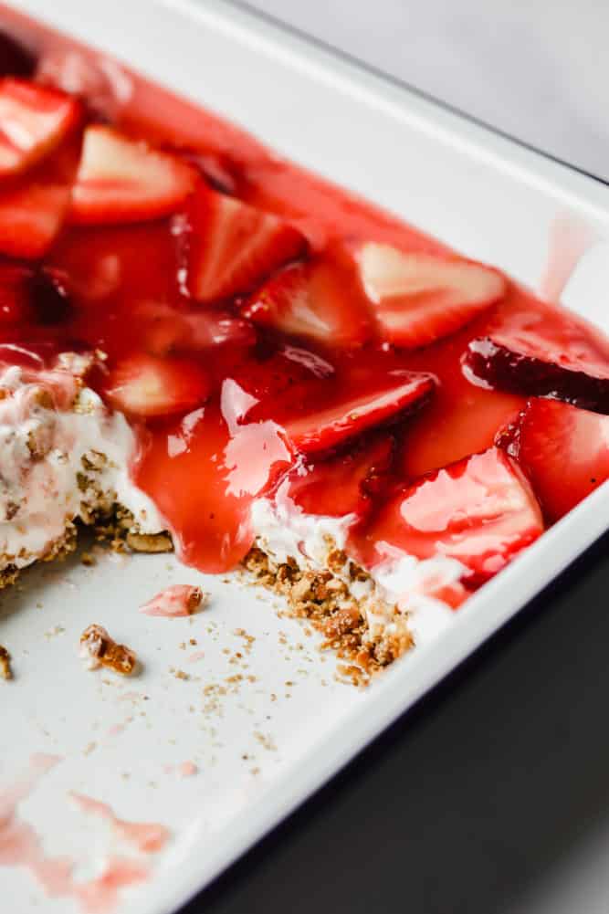 white pan full of a strawberry pretzel salad dessert, a square taken out