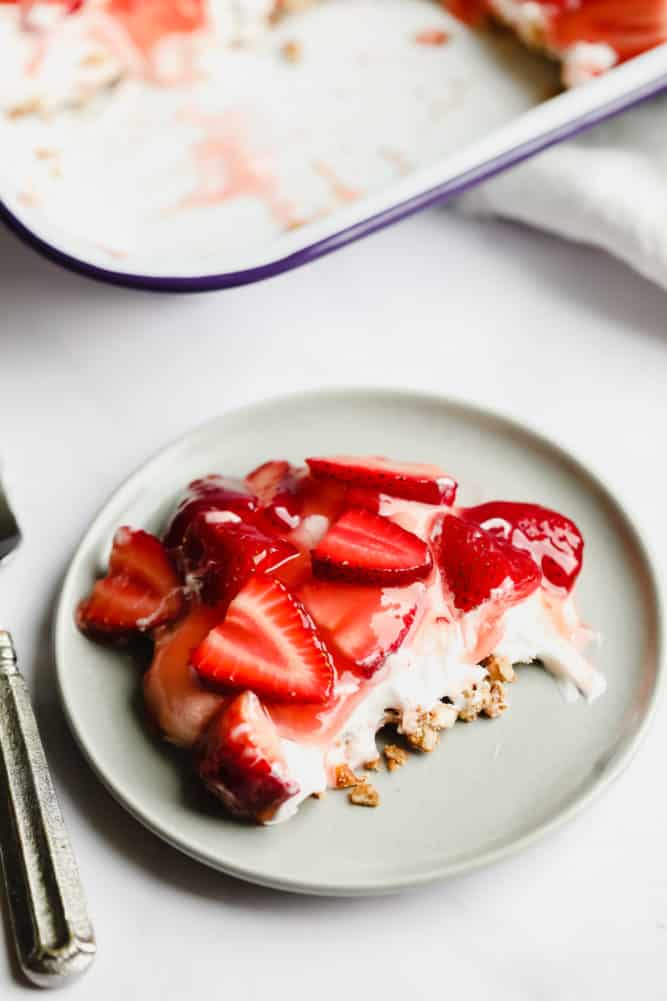 grey plate with crumbly bottom layer, creamy middle and sweet strawberry topping dessert