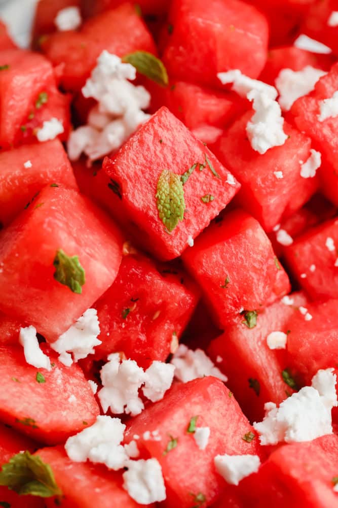 lots of watermelon cubes with mint leaves and feta