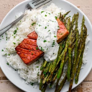 vegan salmon with lemon dill sauce on a plate with rice and asparagus.