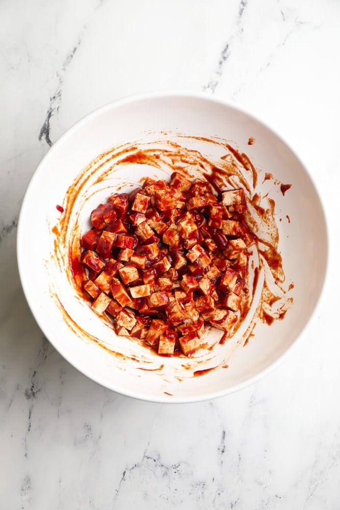 tofu cubes in a bowl with red sauce for pancetta in vegan carbonara