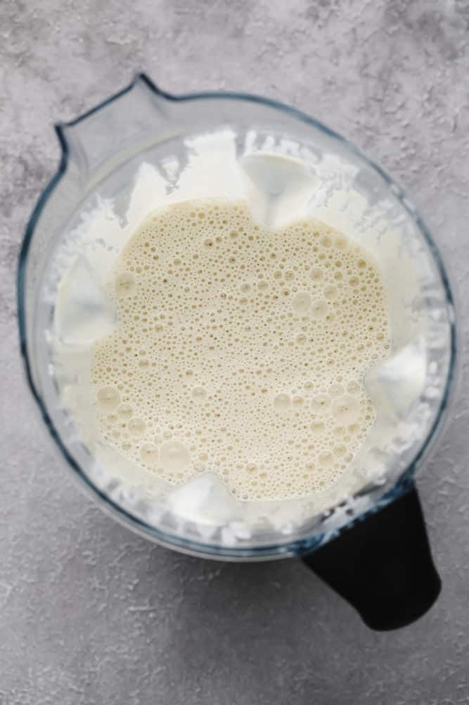 blender with creamy white sauce with bubbles, grey background