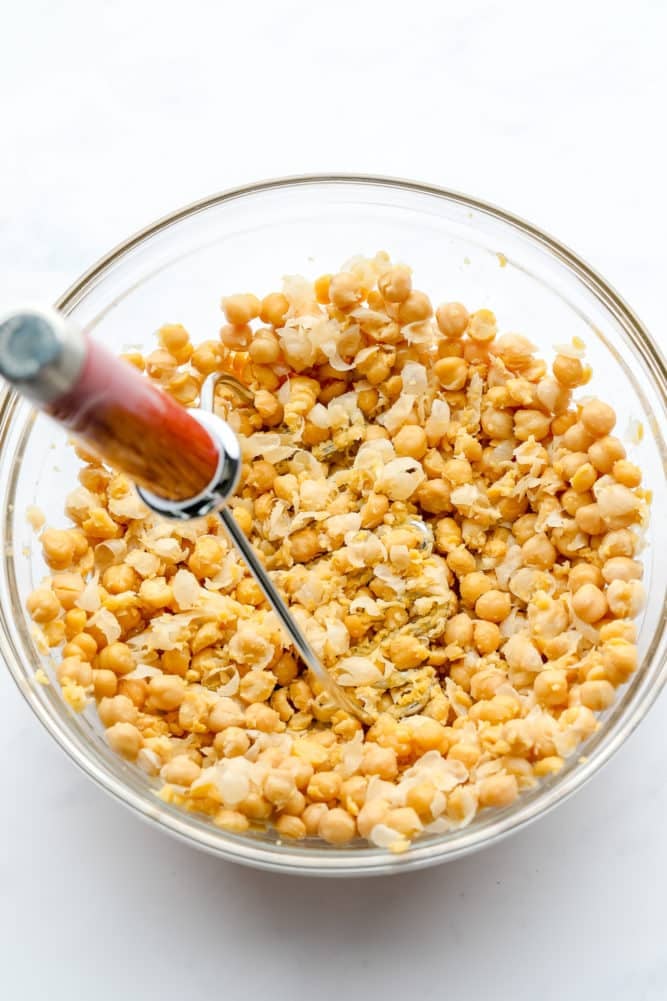 glass bowl with chickpeas being mashed