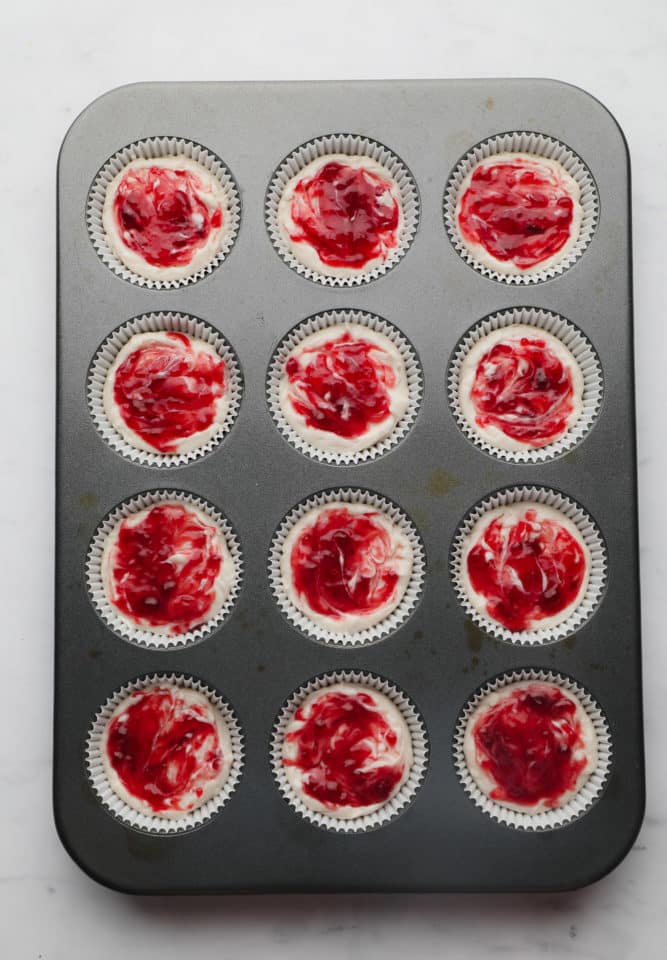 cheesecakes with raspberry swirled into them on muffin pan