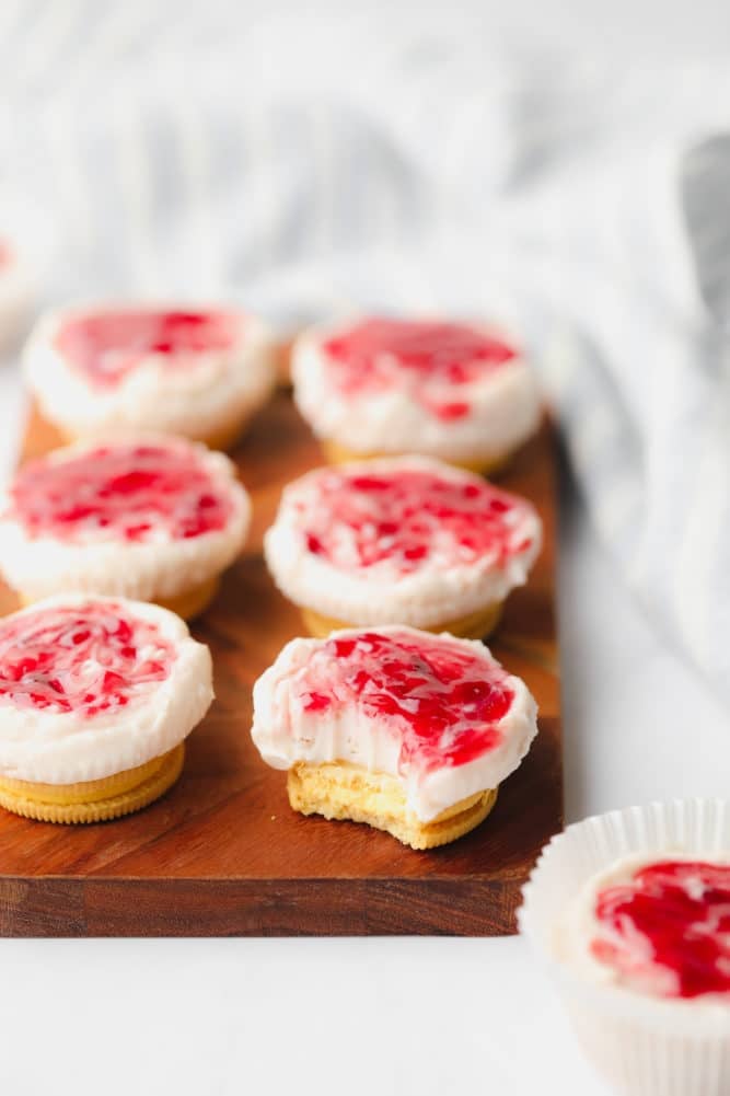 several mini raspberry cheesecakes on board with white background