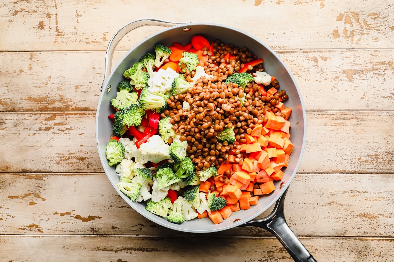 raw chopped vegetables and lentils in a large grey pot.