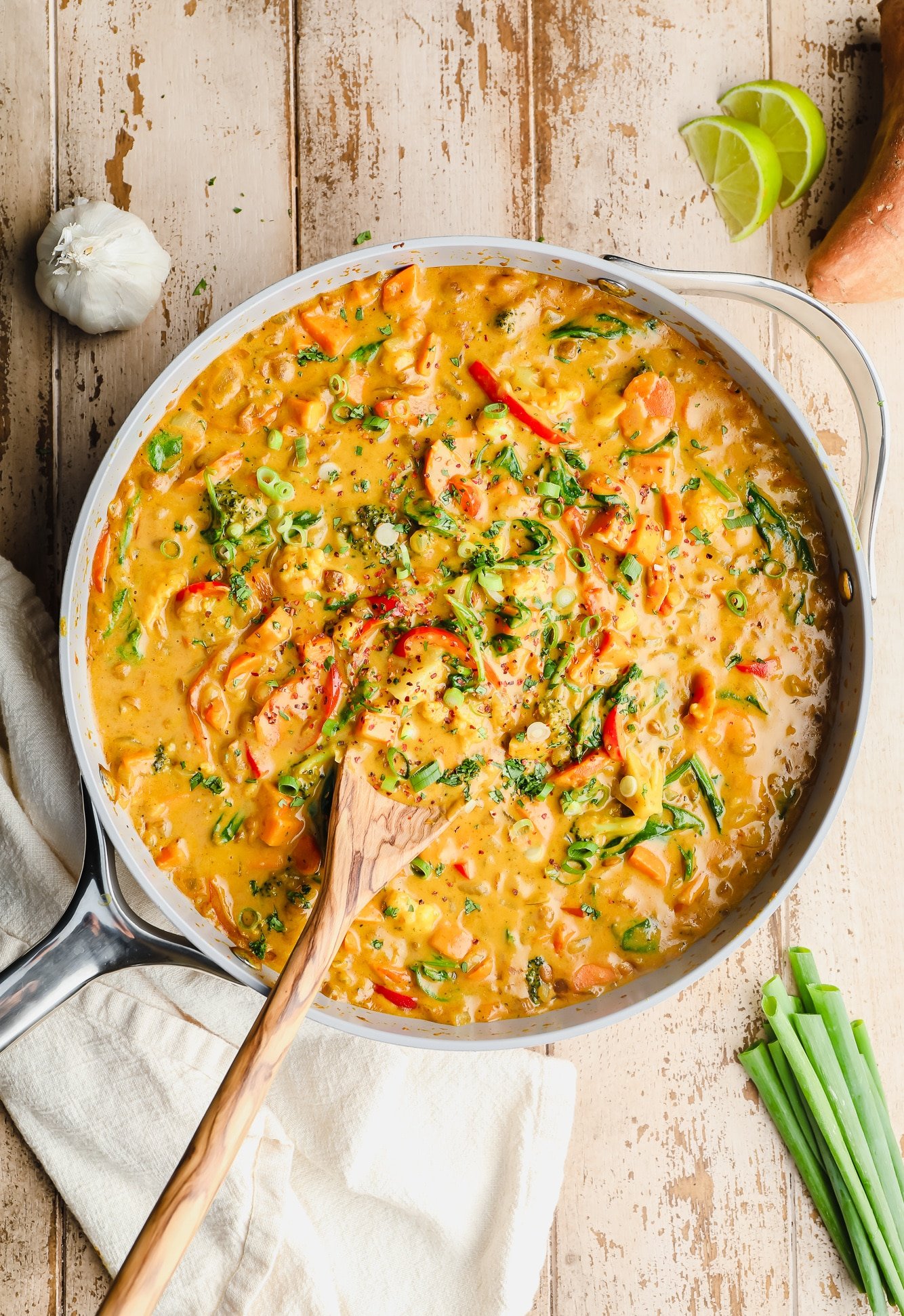 vegan curry in a large grey pot with a wooden spoon sticking out.