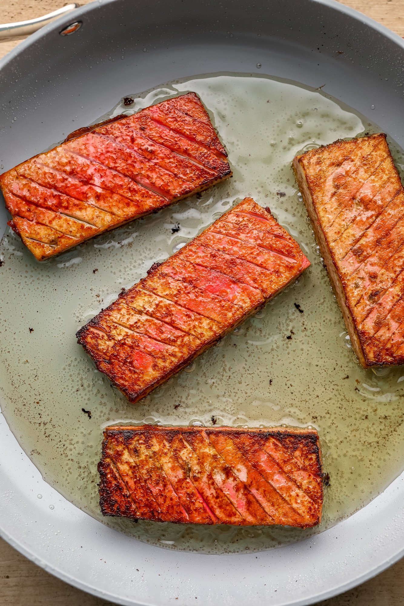 frying 4 pieces of vegan salmon in a skillet.