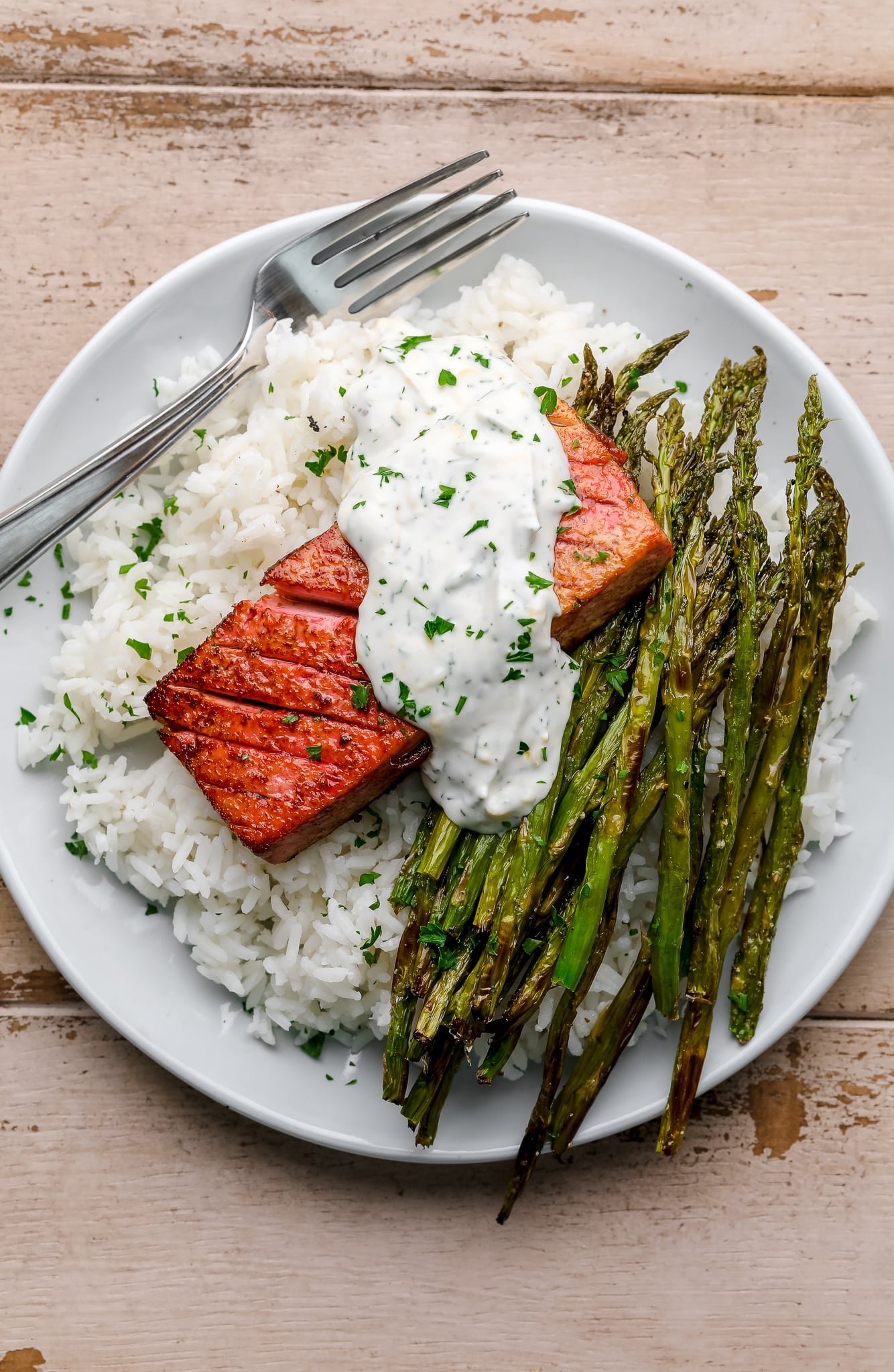 vegan salmon on a bed of rice and asparagus on a white plate.