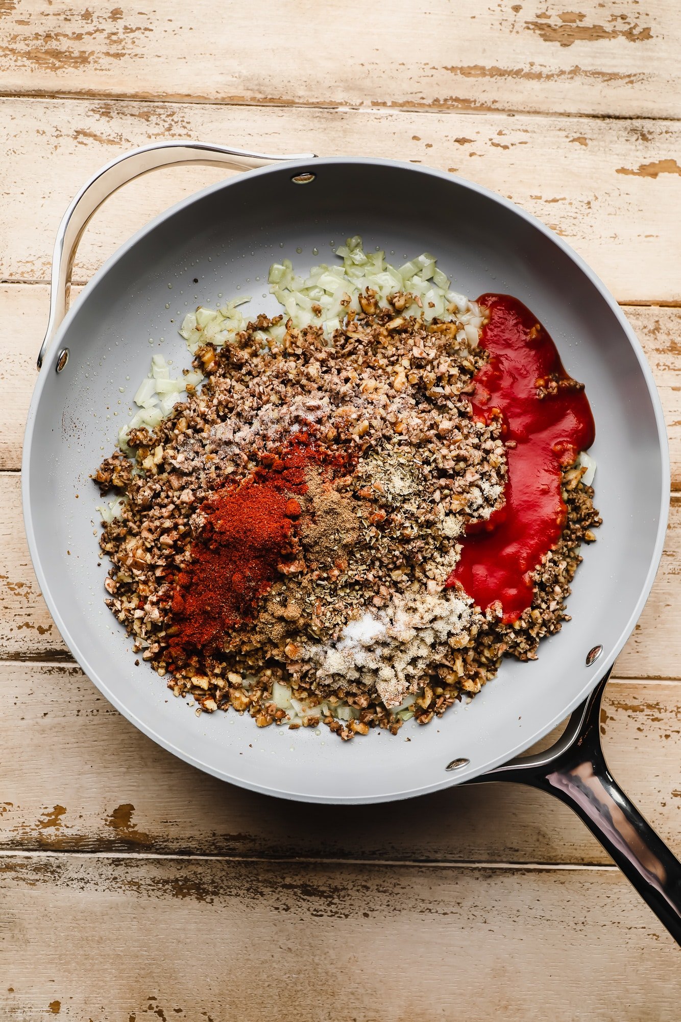 cooking vegan taco meat with spices and tomato sauce in a large grey pan.