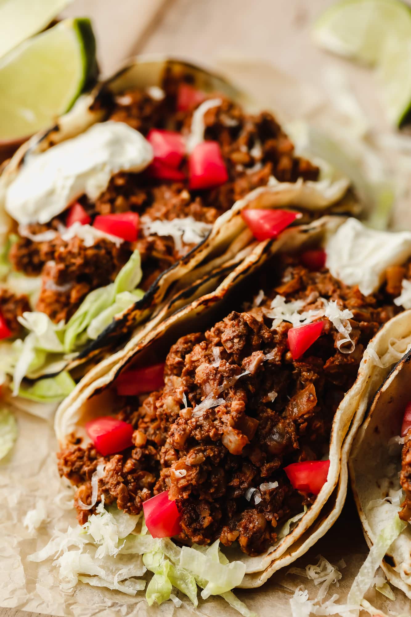 close up on vegan tacos filled with walnut mushroom meat, tomatoes, and lettuce.