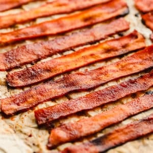 close up on strips of vegan bacon laying on a parchment-lined baking sheet.