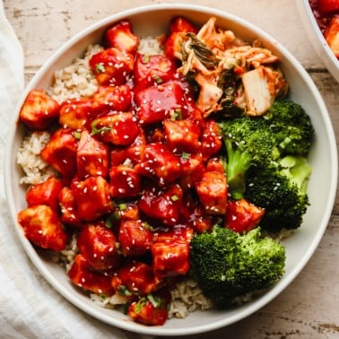 Gochujang Tofu in a white bowl with rice, broccoli, and kimchi.