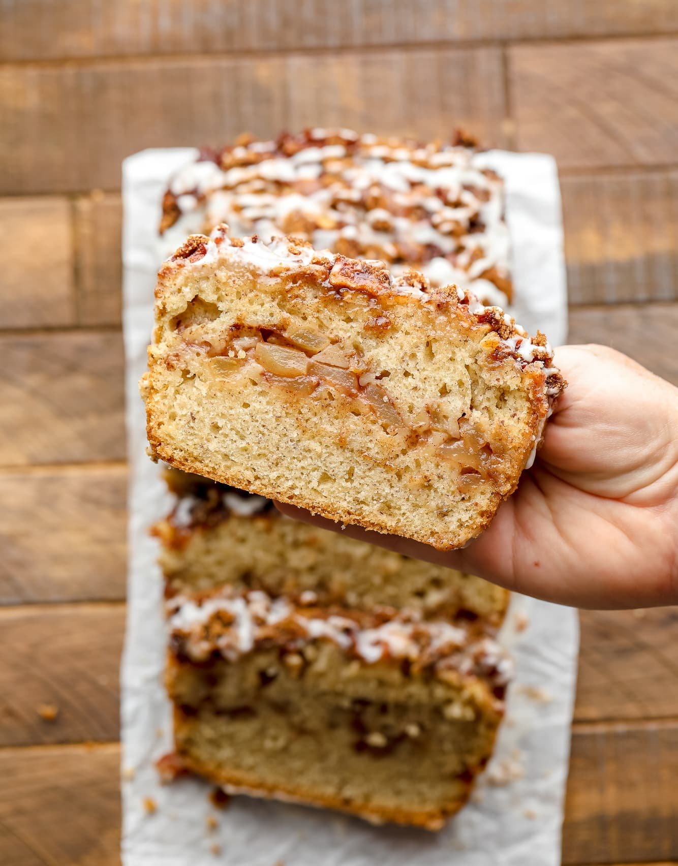 womans hand holding a slice of apple cinnamon bread.