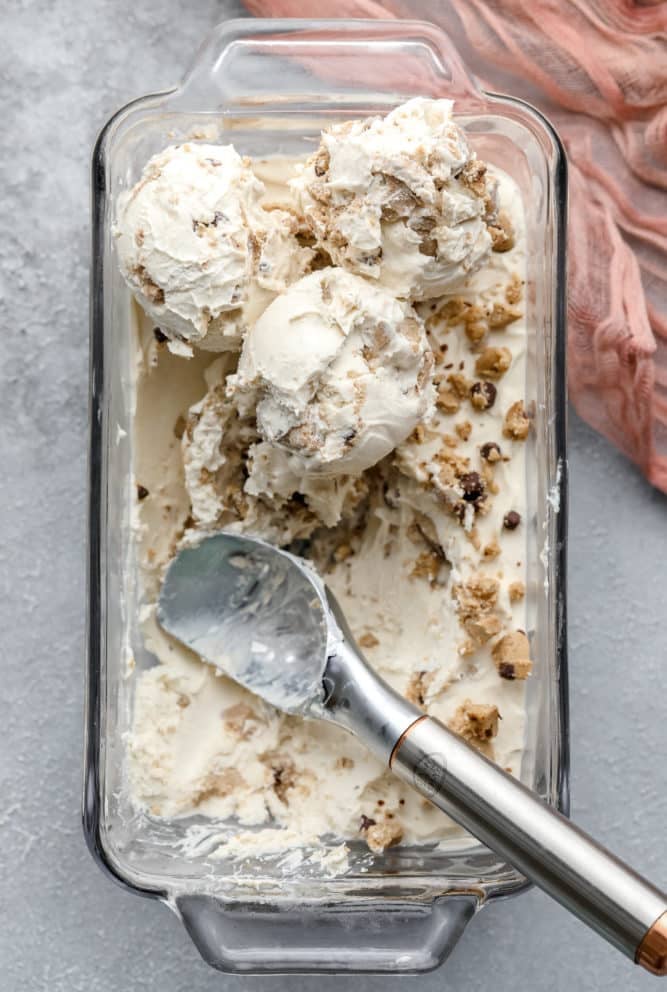 looking down on a glass loaf pan filled with cookie dough ice cream that is mostly white on grey backdrop.