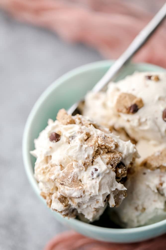 teal bowl with scoops of dairy free ice cream with cookie dough on grey background.