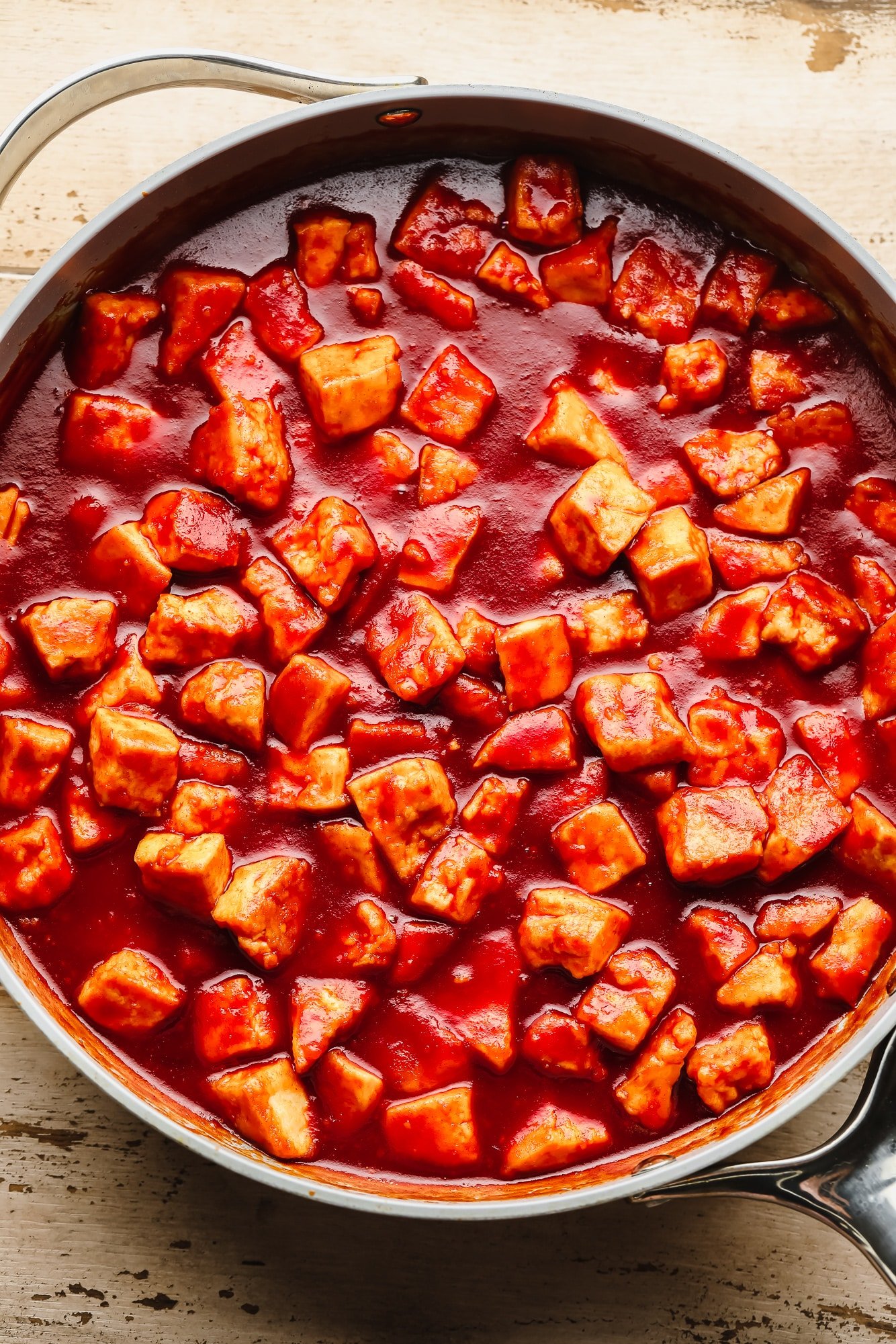 Cooking tofu pieces in a red gochujang sauce in a large skillet.