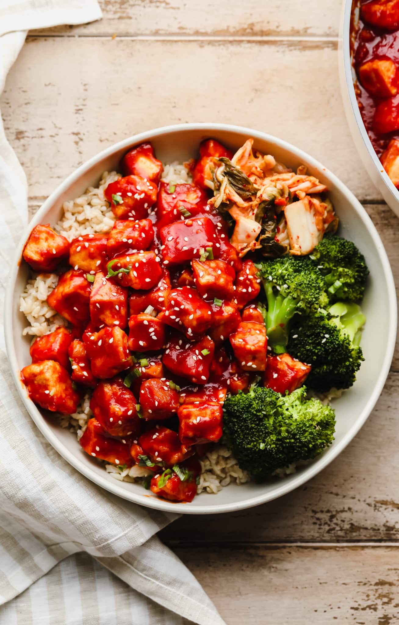 Gochujang Tofu in a white bowl with rice, broccoli, and kimchi.