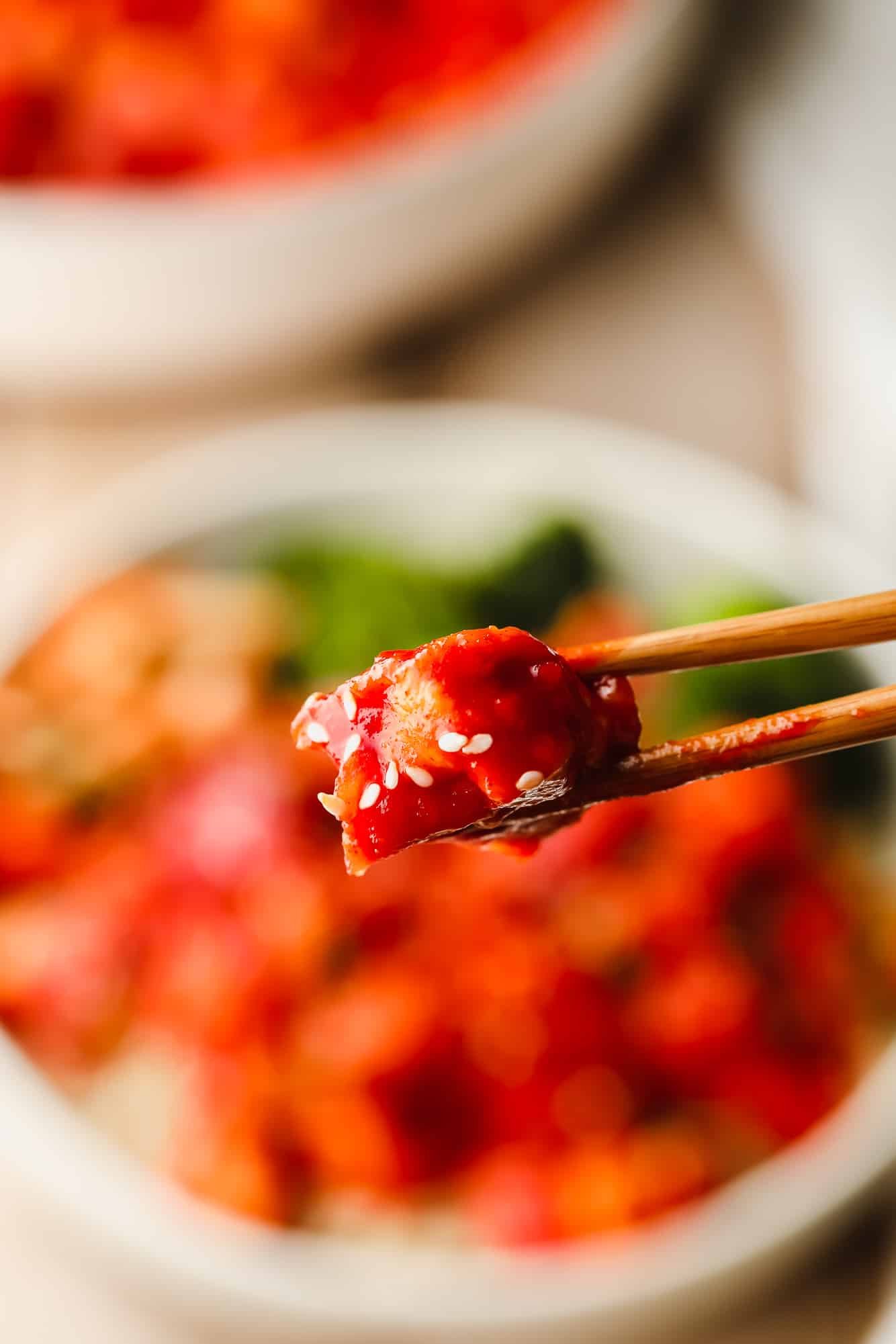 Close up on a piece of Gochujang Tofu between two chopsticks.