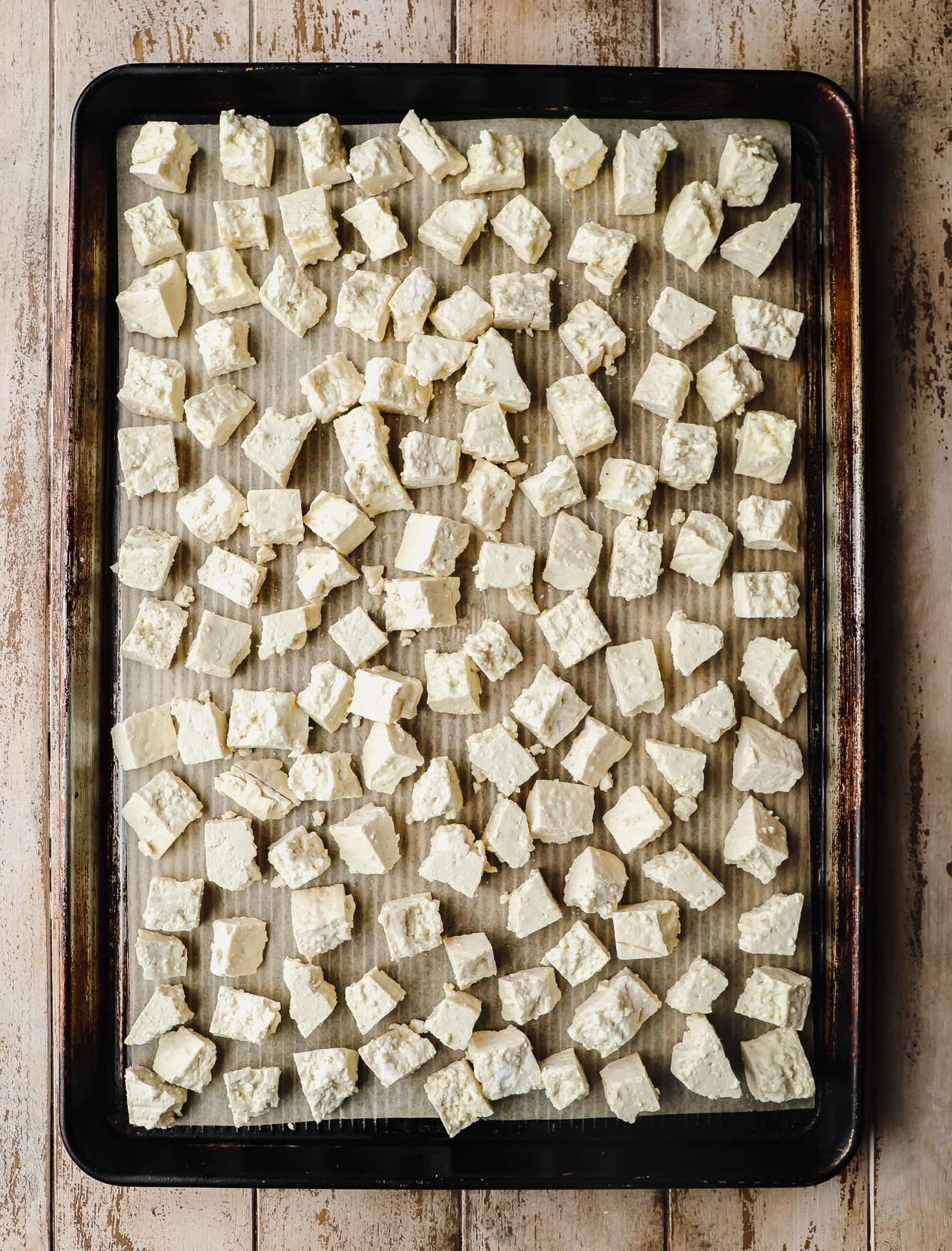 small ripped tofu pieces laying in an even layer on a baking sheet.