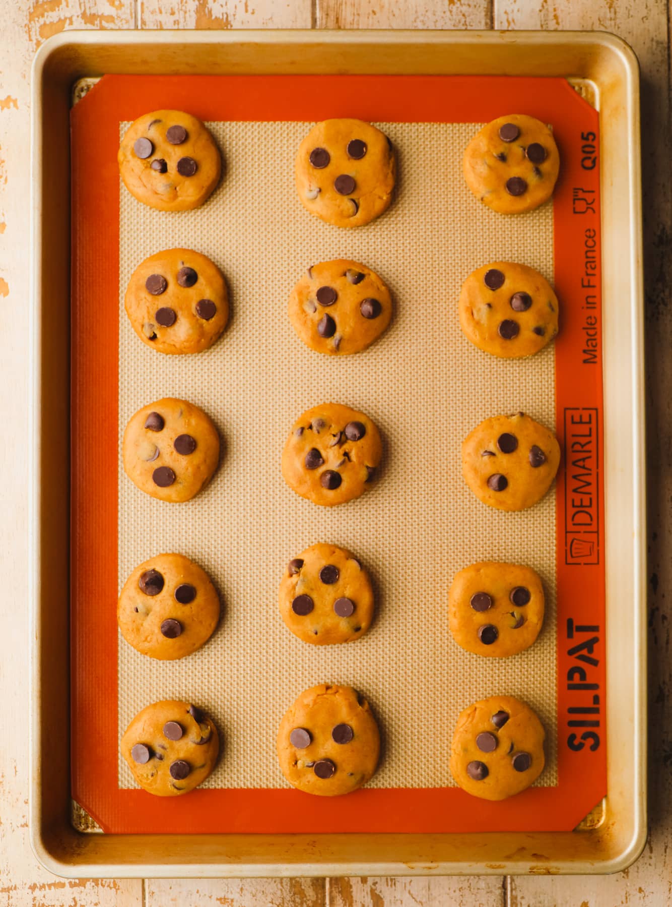 raw pumpkin chocolate chip cookie dough balls in rows on a baking sheet.