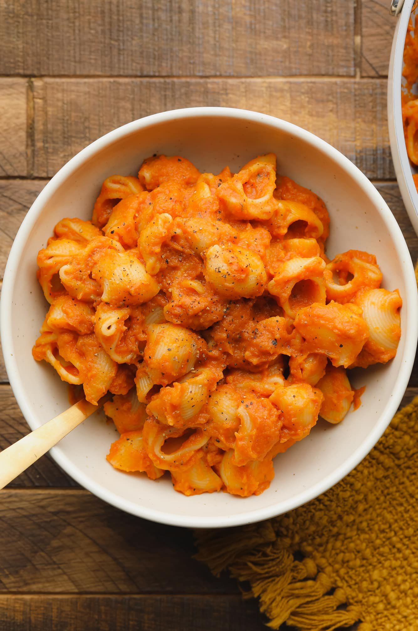 a white bowl filled with pasta covered in pumpkin pasta sauce.