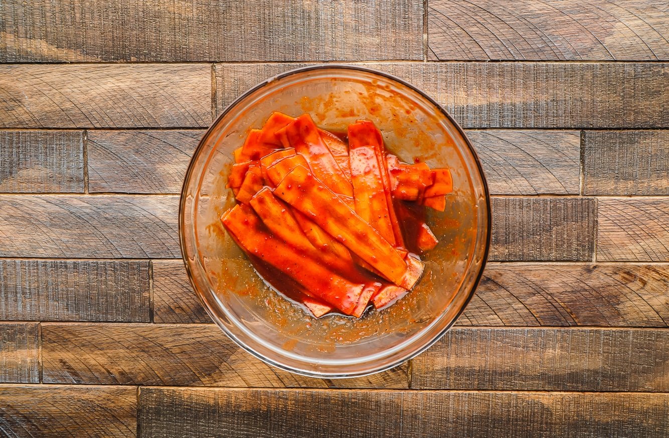 thin carrot strips covered in brown sauce in a glass bowl.