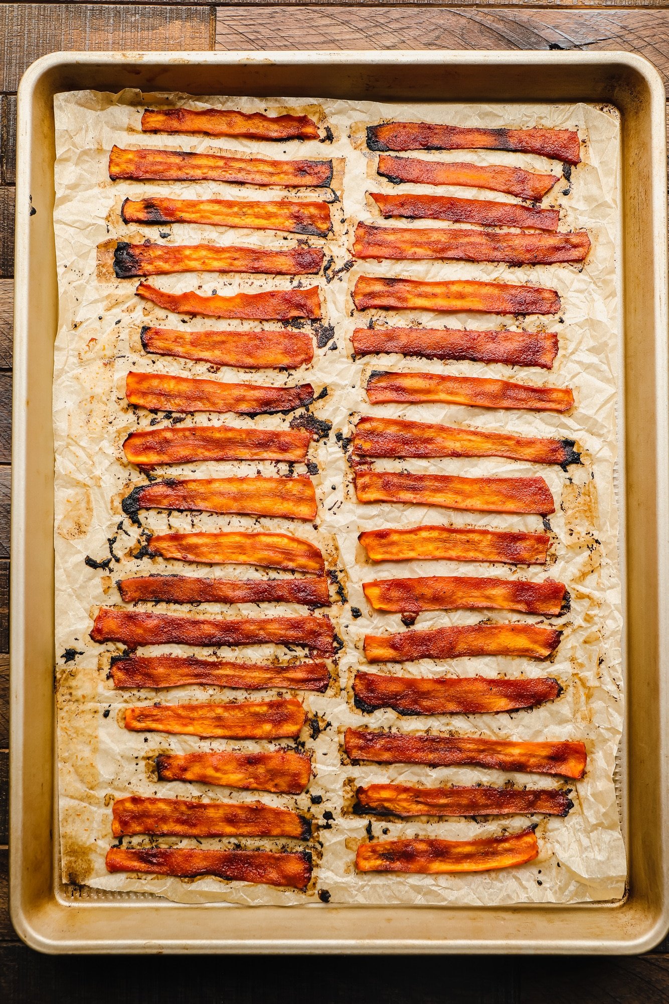 rows of baked vegan bacon on a parchment lined baking sheet.