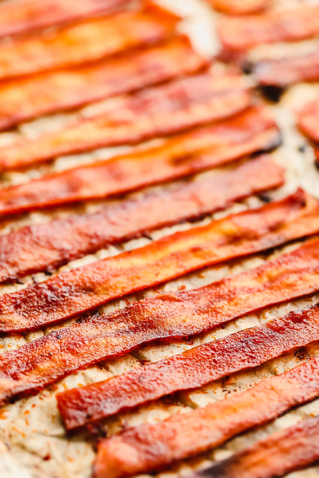 close up on strips of vegan bacon laying on a parchment-lined baking sheet.