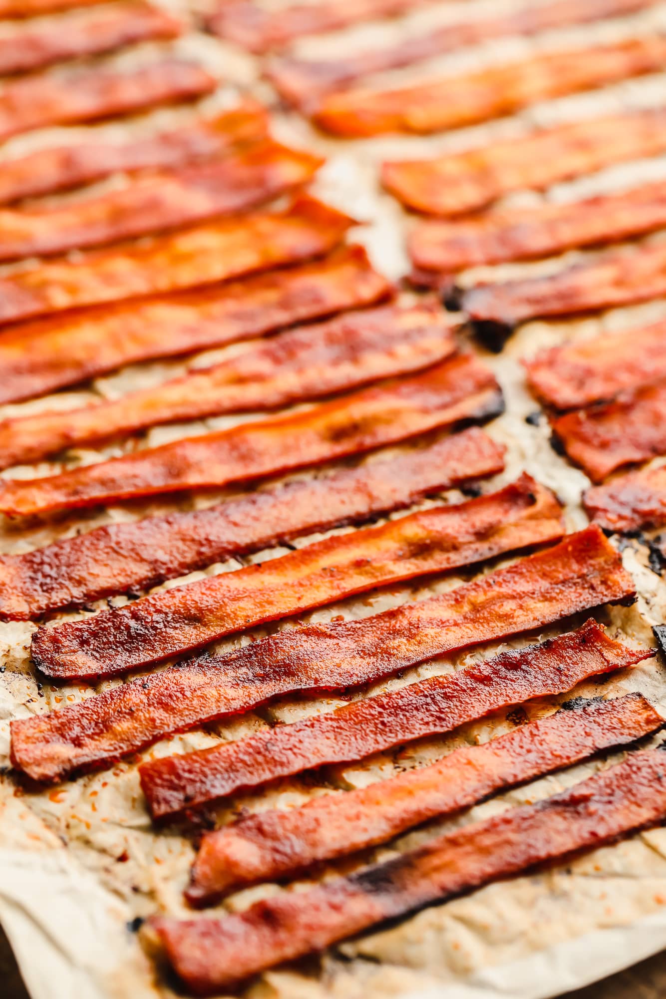 close up on strips of vegan bacon laying on a parchment-lined baking sheet.