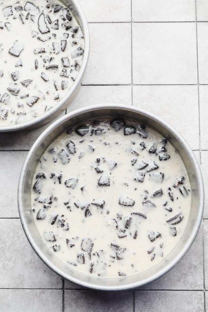 uncooked oreo cake batter in two round pans.