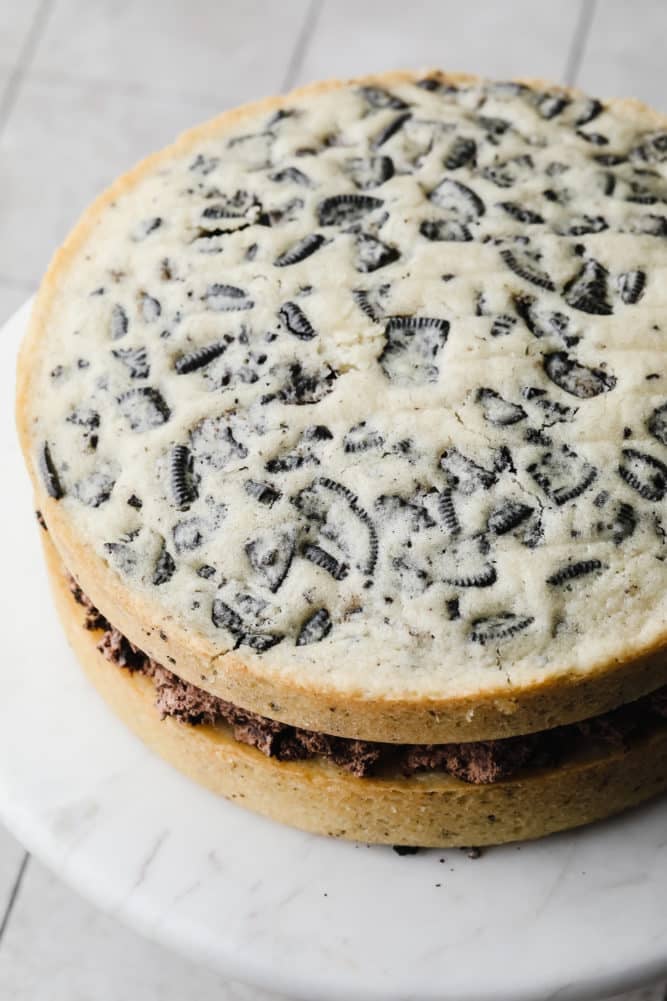 two layers of oreo cake on marble cake stand without frosting.