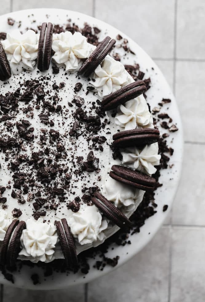 top of an oreo cake showing piped frosting and oreos on a cake stand.