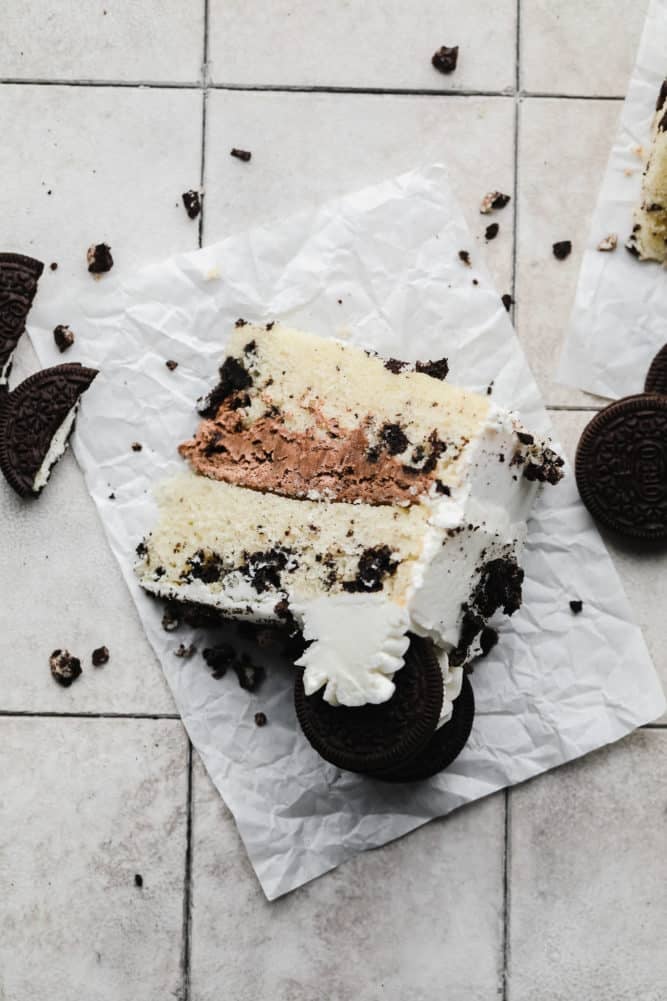 looking down on a piece of cake with whipped chocolate frosting on grey tile background.