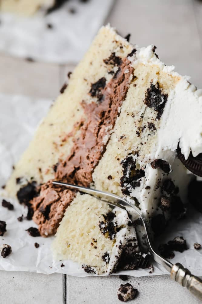 fork cutting into a piece of vegan oreo cake on grey background.