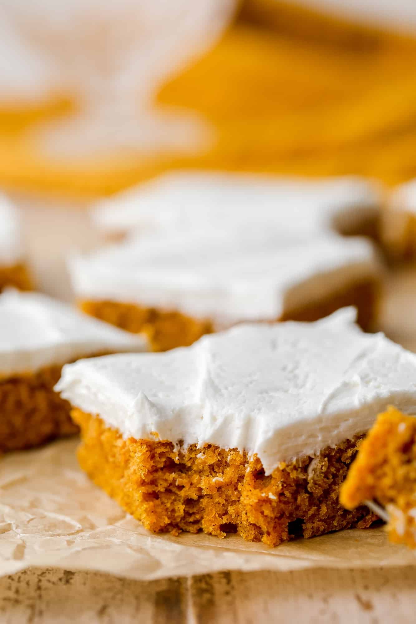 a pumpkin cake bar with cream cheese frosting on top with a bite taken out of it.