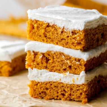 3 vegan pumpkin cake bars stacked on top of each other.