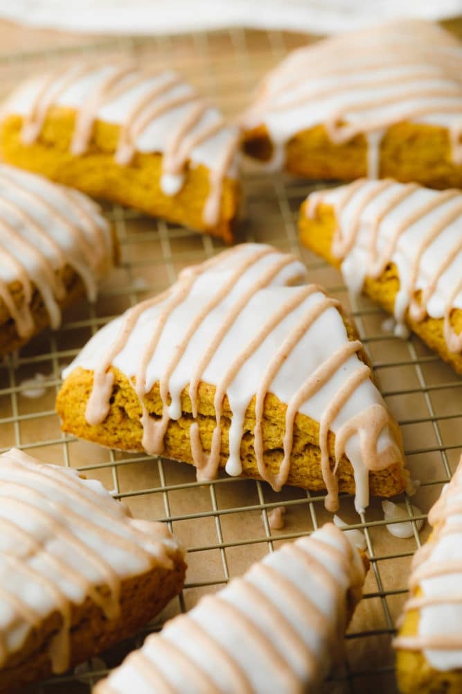 many scones on a cooling rack, orange tan with two glazes.