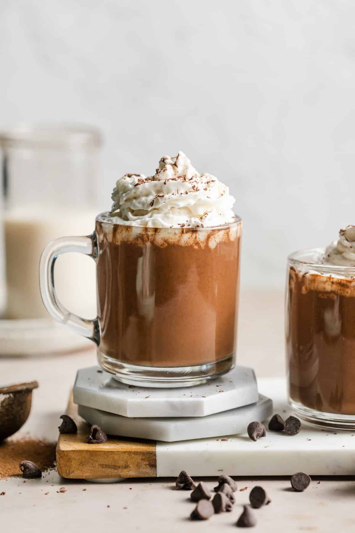 vegan hot chocolate in a glass mug with whipped cream on top.