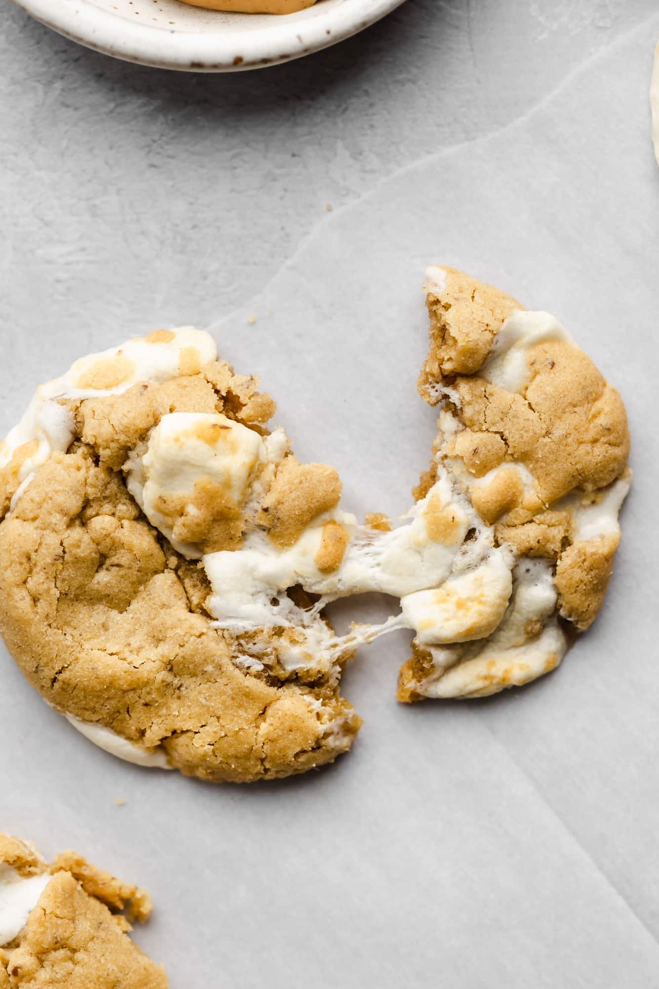 a fluffernutter cookie broken in half on parchment paper.