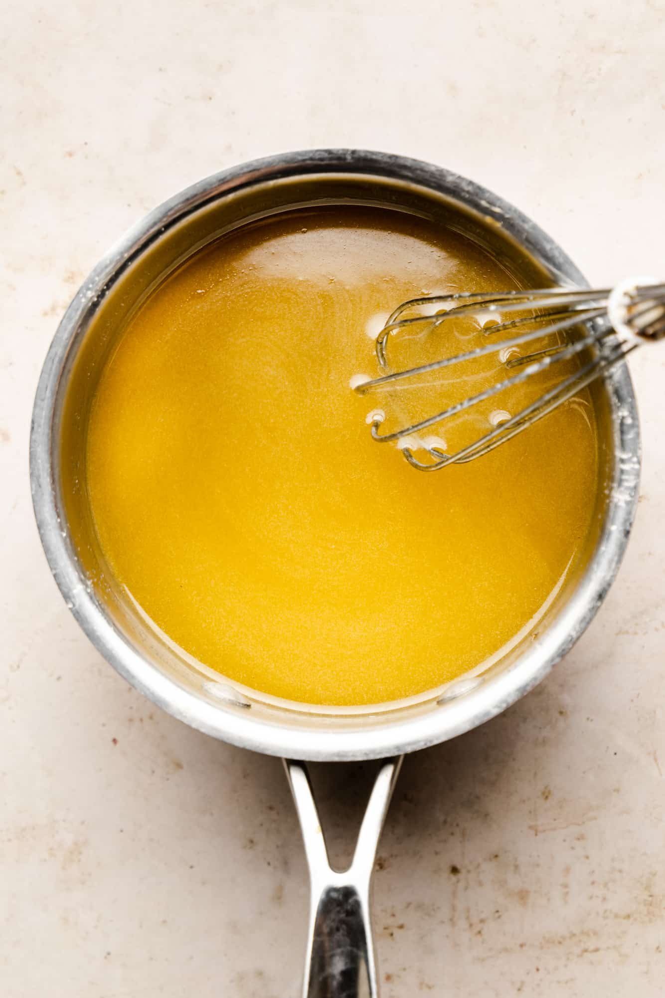 using a whisk to stir a buttery, creamy sauce in a medium saucepan.