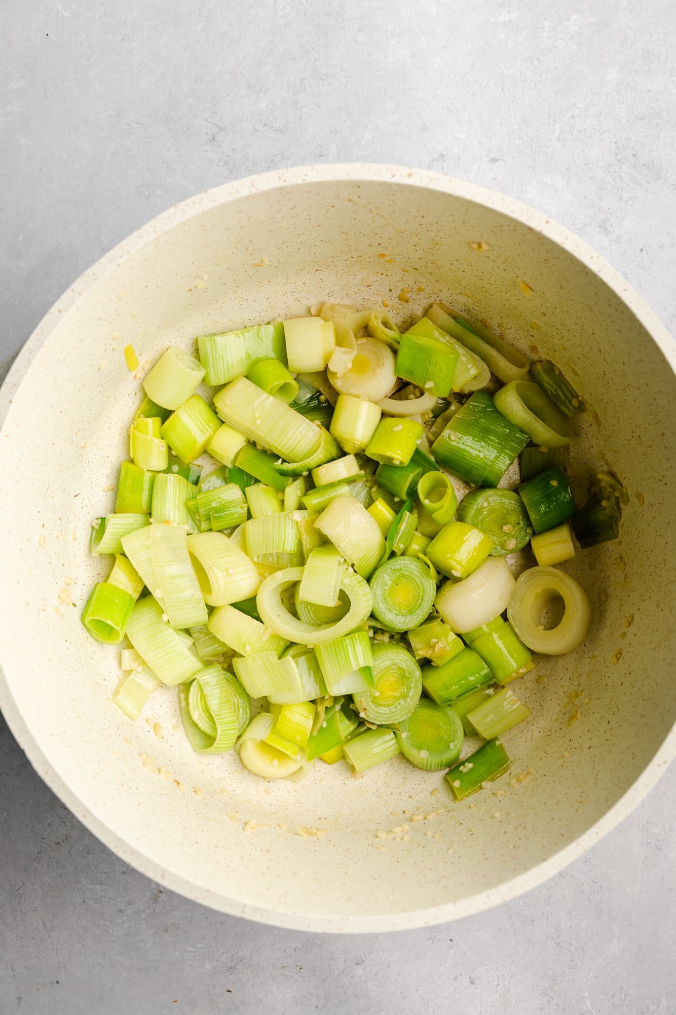 a large white pot with cooked leeks and garlic.