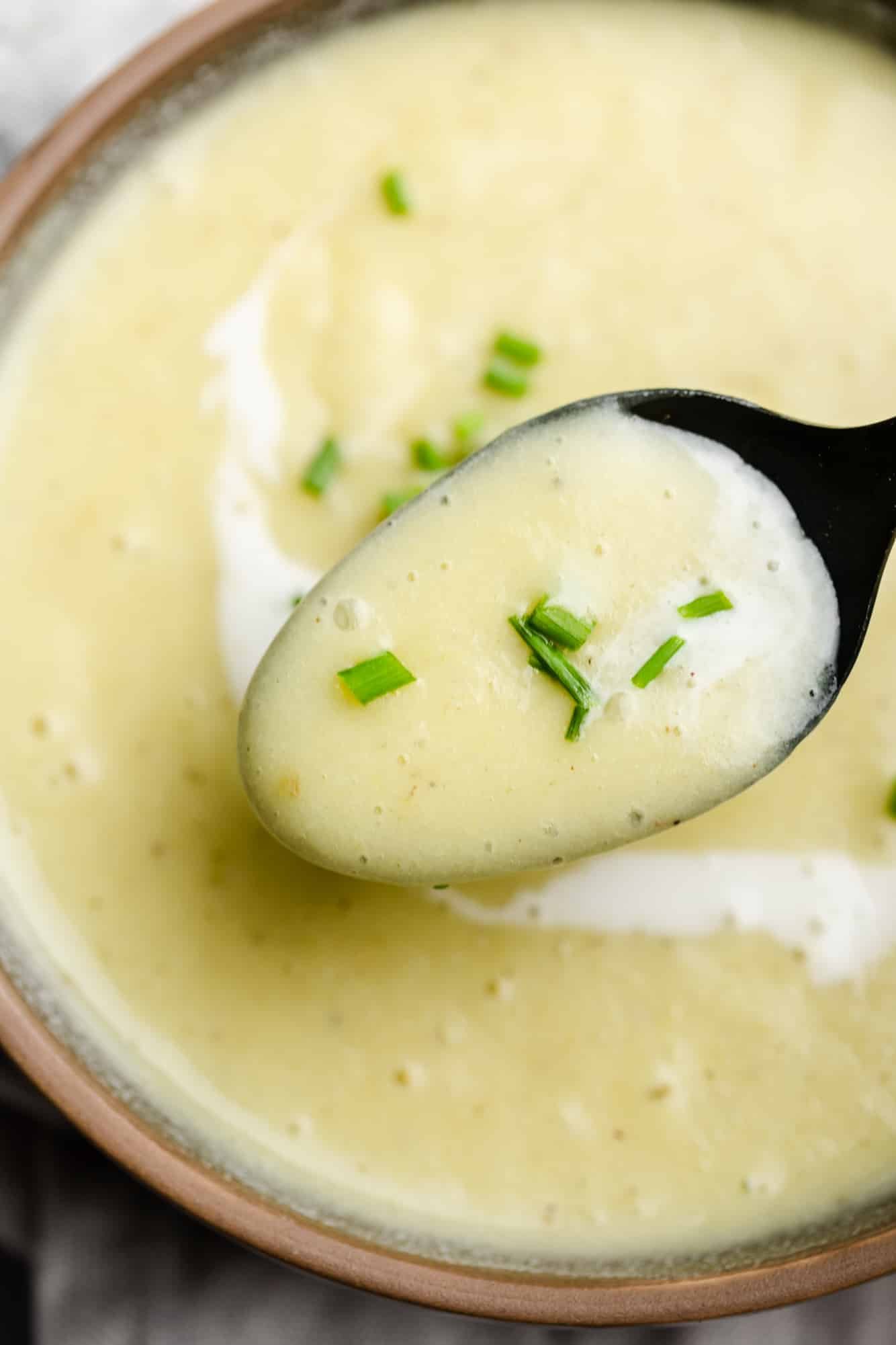 close up on a spoon lifting a scoop of Vegan Potato Leek Soup out of a bowl.