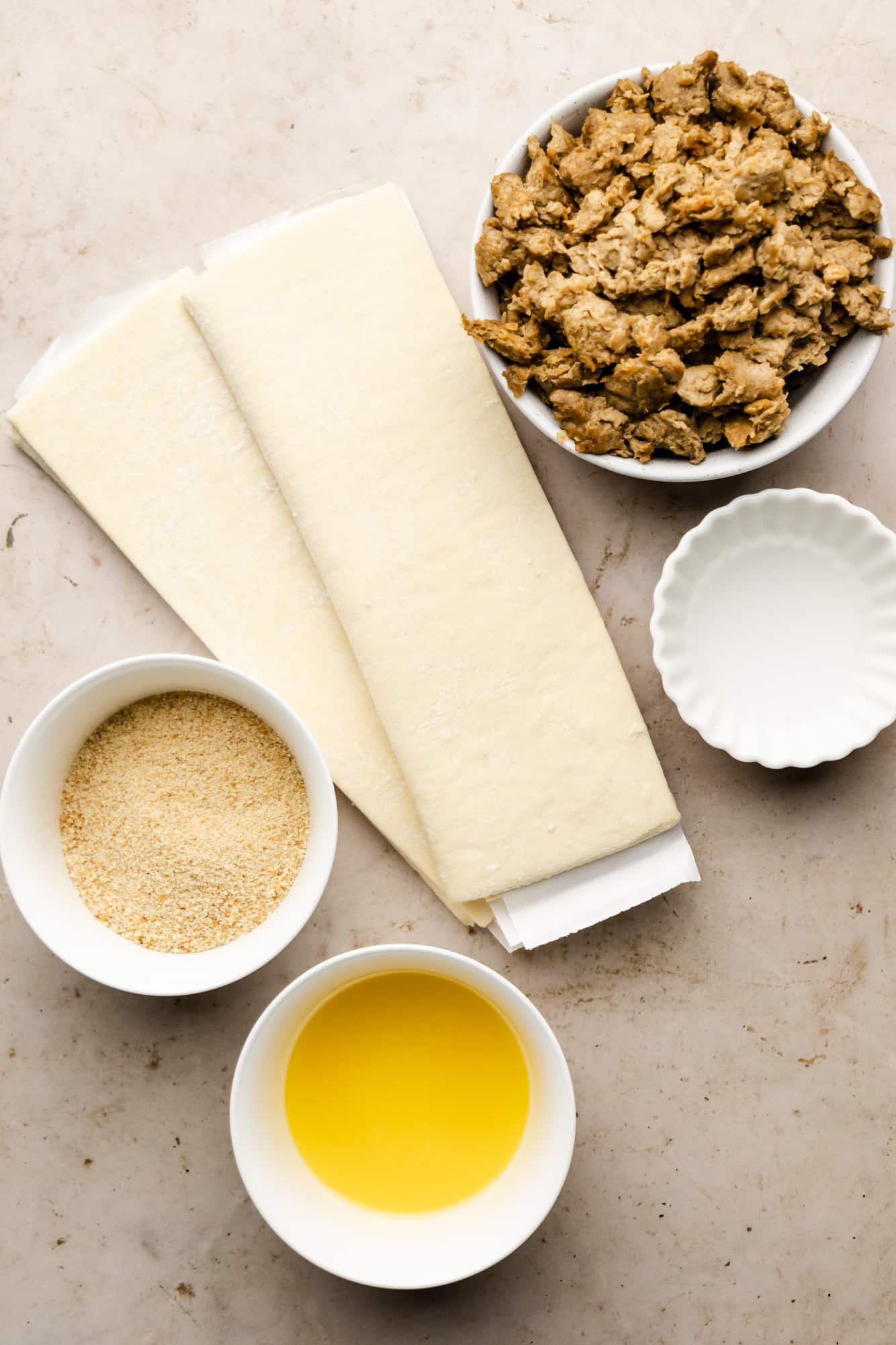 ingredients for vegan sausage rolls in individual white bowls.